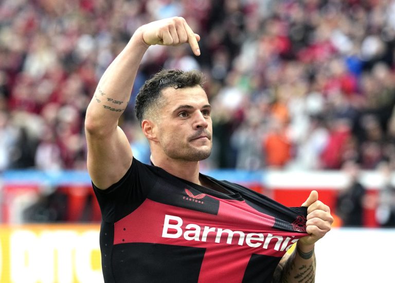 Swiss midfielder Granit Xhaka of Bayer 04 Leverkusen celebrates during a football match, gesturing with one finger pointed skyward and another hand towards his club jersey